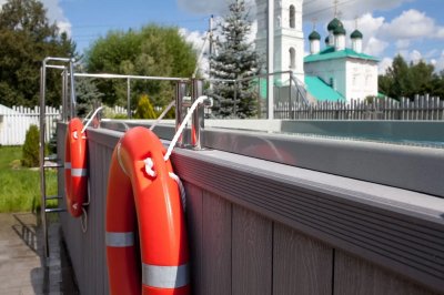 Плавательный СПА с композитным бортиком и перилами рядом с зеленым пейзажем и храмом